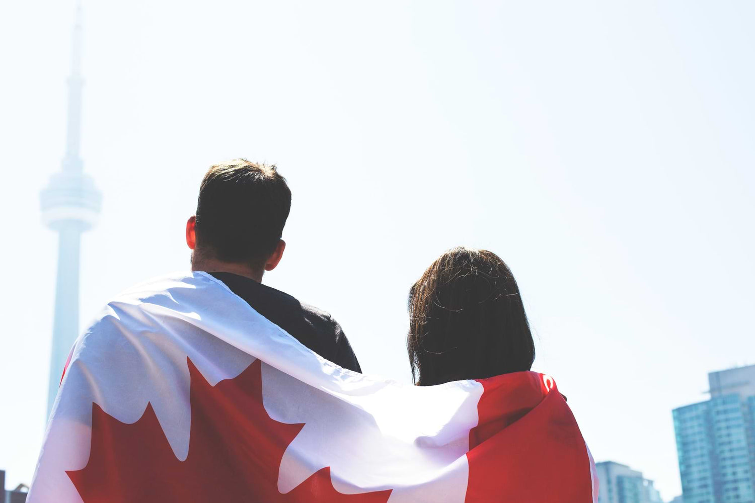 A Couple With Backs Turned Wearing Canadian Flag, Overlooking A City